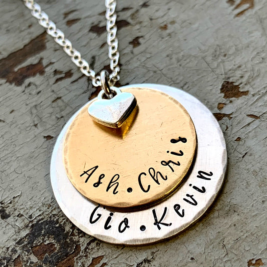 Necklace with two circular pendants, one gold and one silver, engraved with names.