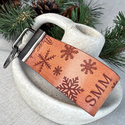 Genuine leather snowflake keyfob with personalized engraved initials on brown leather, handmade holiday keychain.
